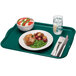 A teal Cambro rectangular tray with food on it and a fork.