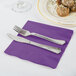 A knife and fork on a purple Creative Converting luncheon napkin.