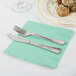 A plate with a fork and knife on a mint green Fresh Mint Green luncheon napkin.