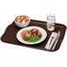 A brown Cambro rectangular tray with food on it and a fork.