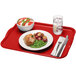 A red Cambro rectangular tray with food, a fork, and a knife on it.