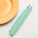 A fork in a Fresh Mint Green Creative Converting dinner napkin next to a plate.