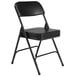 A National Public Seating black steel folding chair with black vinyl padding.