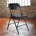 A black National Public Seating folding chair with black vinyl padding on the seat and back.