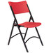 A National Public Seating black metal folding chair with red plastic back and seat.