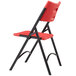 A National Public Seating black metal folding chair with red plastic back and seat.
