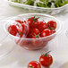 A plastic container of tomatoes and salad on a table.