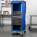 A blue Regency bun pan rack cover on a rolling cart with trays.