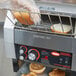 A person putting bread into a Hatco conveyor toaster.