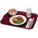 A Cambro rectangular burgundy fiberglass tray with a plate of food, bowl of salad, and a fork.