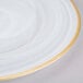 A white glass charger plate with a gold rim.