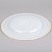 A white Charge It by Jay glass charger plate with a gold rim.