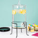 A Stylesetter glass beverage dispenser with water and lemons on a table.