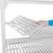 A white hand holding a vented Cambro Camshelving® shelf.