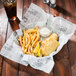American Metalcraft newspaper print deli wrap paper in a cone basket with french fries and a bowl of white sauce.