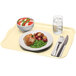 A rectangular Cambro fiberglass tray with food, a glass of water, a fork, and a knife on a napkin.