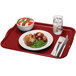 A cherry red Cambro rectangular fiberglass tray with food, a fork, and a knife on it.