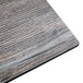 A BFM Seating rectangular driftwood composite laminate table top with a knife edge on a table.