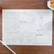 A Doodletown Fun placemat with drawings on it on a table with food.