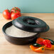 A black pan with a round black "Tortilla Pleezer" container and food inside.