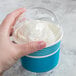 A hand holding a blue Choice paper cup of frozen yogurt with a white lid.