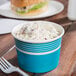 A blue and white container with food in it on a table with a plastic fork.