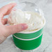 A hand holding a green Choice paper cup filled with ice cream.