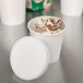 A close up of a white Choice paper cup filled with ice cream and topped with a white paper lid.