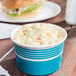 A blue paper cup filled with macaroni and cheese.