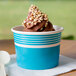A close up of a Choice blue paper cup filled with chocolate ice cream and nuts.