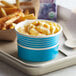 A blue container with macaroni and cheese on a tray with french fries.