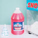 A jug of Carnival King Cotton Candy Snow Cone Syrup next to a cup of snow.