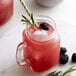A glass mug of Monin Blackberry Fruit Puree lemonade with a straw on a white background.