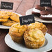 A plate of muffins with Tablecraft chalkboard picks on them.