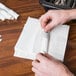 A person cutting white paper napkin bands.