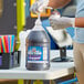 A person pouring Carnival King grape snow cone syrup into a container.