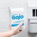 A hand holding a box of GOJO lotion skin cleanser.