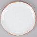 A white plate with brown speckled irregular edges.