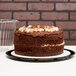 A close-up of a chocolate cake in a clear plastic container with a clear dome lid.