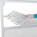 A person adding a white solid shelf to a Cambro Camshelving unit.