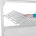 A person assembling a Cambro Camshelving Premium stationary unit with white vented and solid shelves.