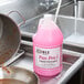 A pink bottle of Noble Chemical Pan Pro liquid detergent on a counter next to a pan and a sink.