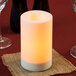 A white flameless Sterno outdoor banquet pillar candle on a burlap napkin.