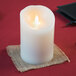 A close-up of a Sterno Mirage cream LED candle on a table.
