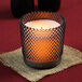 A Sterno flameless wax filled glass candle lamp with a hobnail design on a table in a winery cellar.