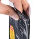 A hand opening a black plastic Menu Solutions bag.