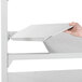 A person adding a white Cambro Camshelving® Premium shelf to a unit.