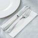A silver fork and knife on a white Hoffmaster FashnPoint dinner napkin.