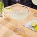 A Libbey Fiesta Grande Margarita Glass with a drink and a lime slice on a table.