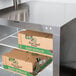 A metal shelf with boxes of spinach inside a Traulsen undercounter refrigerator.